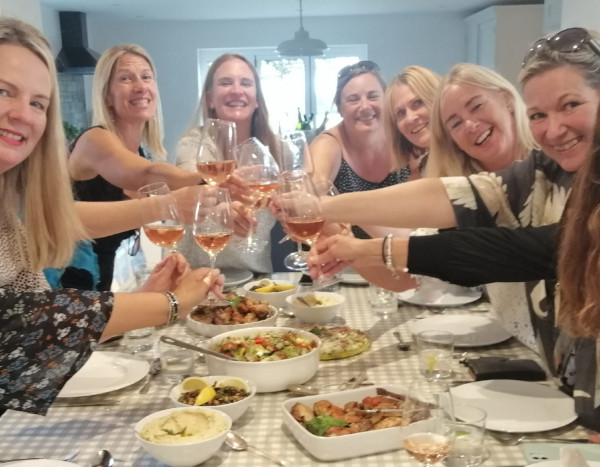 A group of women clinking glasses over a table of food