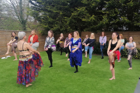 Lots of women belly dancing in a garden