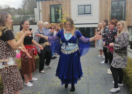 A woman walking in between her friends who are showering her with petals at a hen party