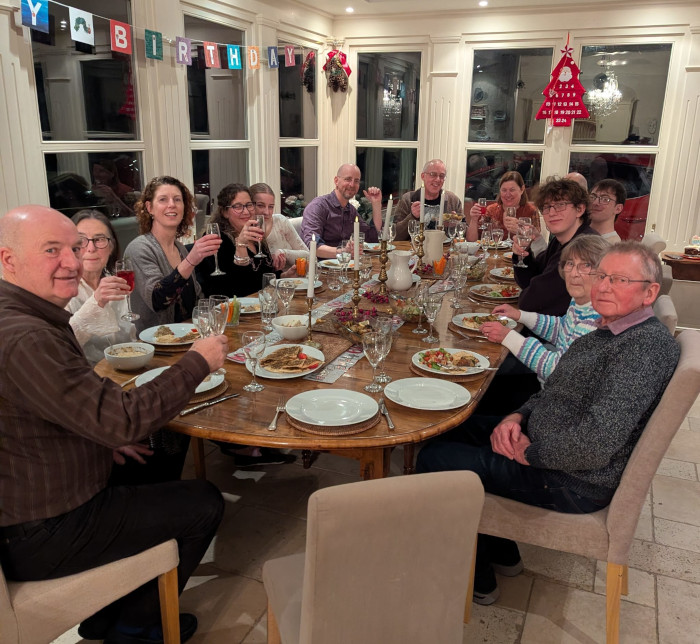 Large group of people round a dining room table with Lebanese food celebrating a birthday